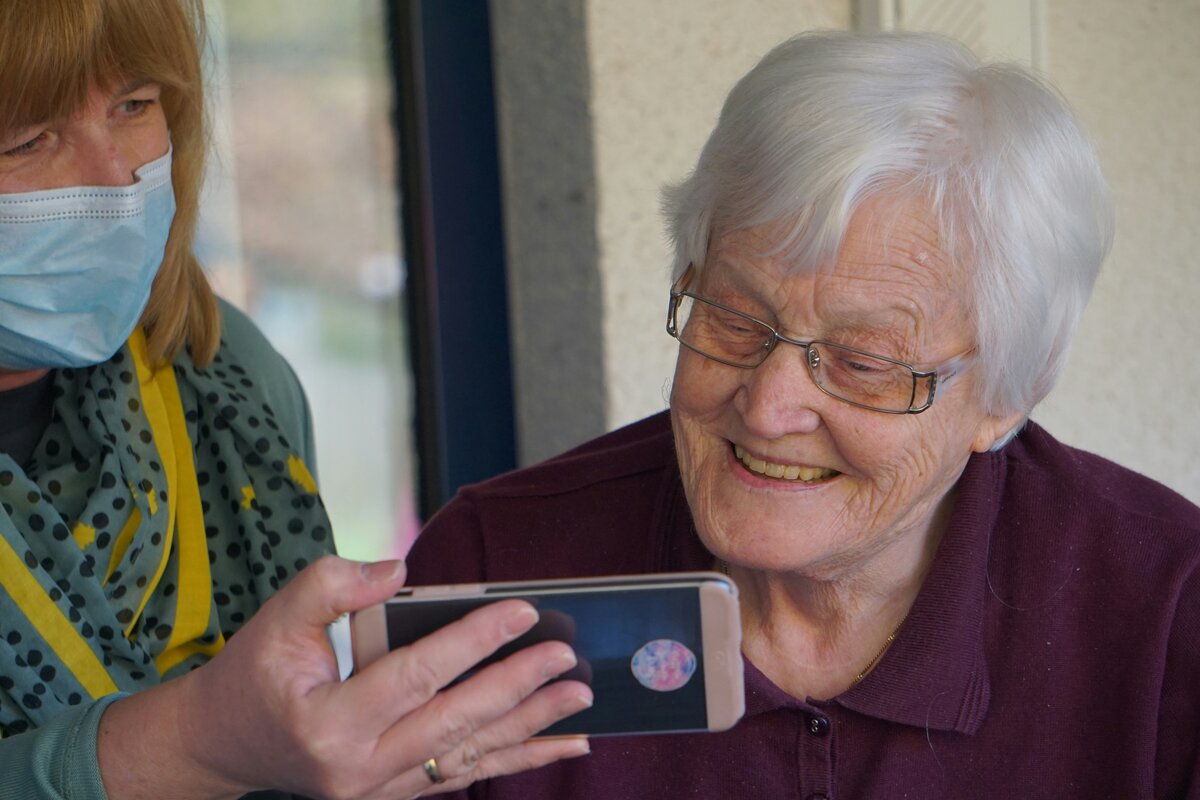 Caregiver helping senior resident with technology during family consultation